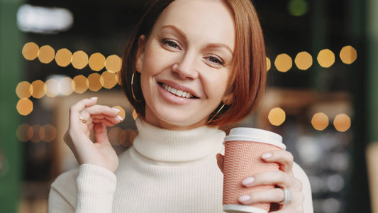 Femeie cu zâmbet alb ținând o ceașcă de cafea.